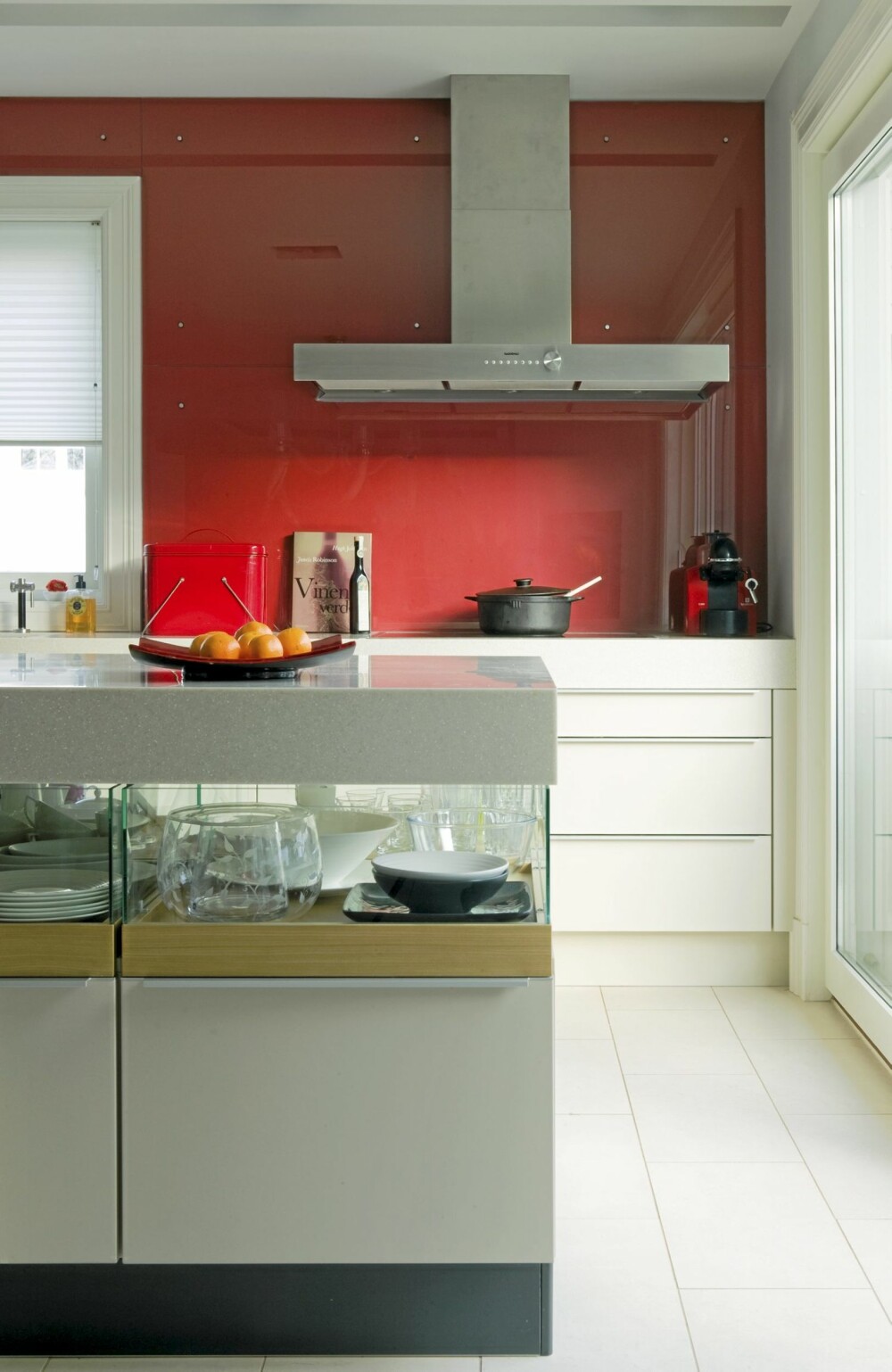RØD SKVETTSONE. Kjøkkeninnredningen er fra Poggenpohl. HiMacs benkeplate i fargen Sea Oat Quartz. Hele den røde veggen er dekket av glass. RØD SKVETTSONE. Kjøkkeninnredningen er fra Poggenpohl. HiMacs benkeplate i fargen Sea Oat Quartz. Hele den røde veggen er dekket av glass.