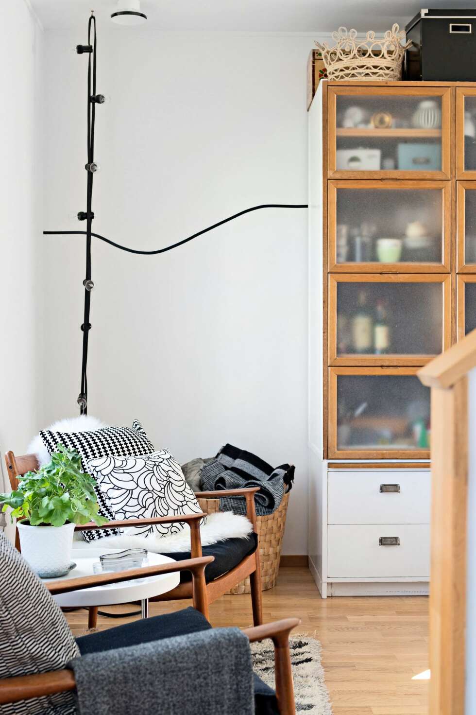 FIFFIG LYSLØSNING: Familien liker å innrede med tremøbler og tilbehør i svart og hvitt. De gamle stolene har Sofie arvet av mormoren, og putene med grafisk trykk er fra Ikea.
I hjjørnet henger en lysslynge fra Granit fra taket. FOTO: Emma Olai FIFFIG LYSLØSNING: Familien liker å innrede med tremøbler og tilbehør i svart og hvitt. De gamle stolene har Sofie arvet av mormoren, og putene med grafisk trykk er fra Ikea.
I hjjørnet henger en lysslynge fra Granit fra taket. FOTO: Emma Olai