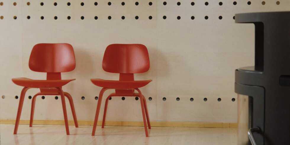 DESIGN I HØYSETET: Her ser du en snipp av skillleveggen som deler leiligheten i Ullevål Hageby i to. Foran to røde Vitra finerstoler designet av Charles Eames. De matsjer dette rene, stramme interiøret perfekt. DESIGN I HØYSETET: Her ser du en snipp av skillleveggen som deler leiligheten i Ullevål Hageby i to. Foran to røde Vitra finerstoler designet av Charles Eames. De matsjer dette rene, stramme interiøret perfekt.