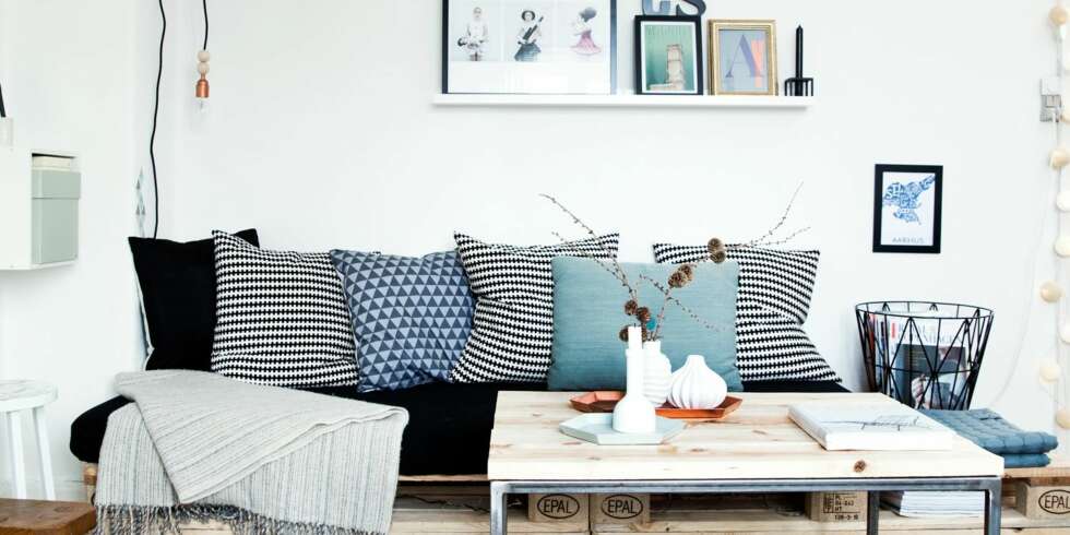 PALLESOFA: Hvitt, grått og støvet blått gjør stuen lys og trivelig. Pallesofaen med lyst tre understreker den skandinaviske stilen. PALLESOFA: Hvitt, grått og støvet blått gjør stuen lys og trivelig. Pallesofaen med lyst tre understreker den skandinaviske stilen.