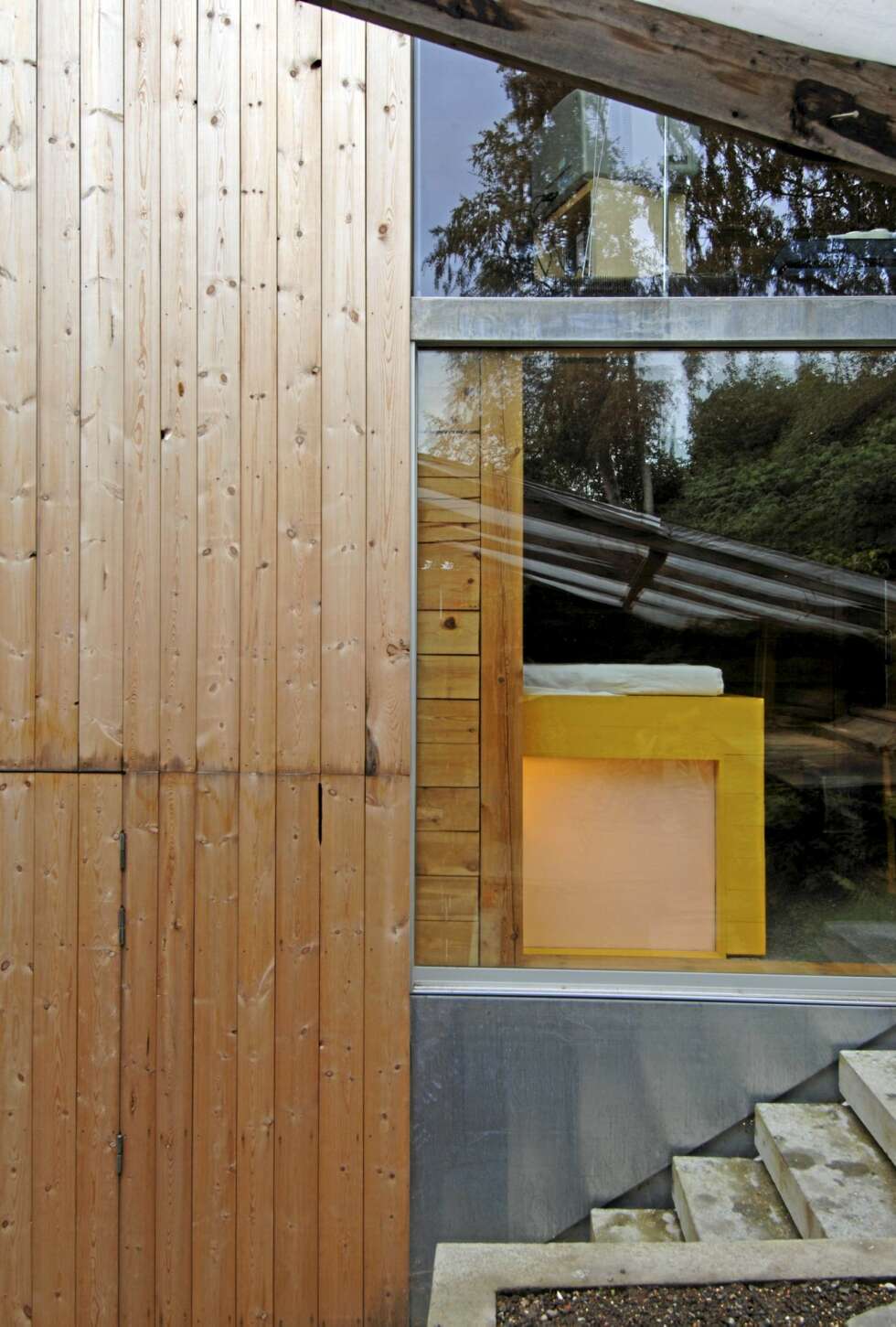 SPENSTIG ARKITEKTUR: Terrengtrappen leder til terrassen som ligger mot skrenten bak huset. Her ser vi også allrommet og en flik av det knallgule soverommet. Under det skjermer matte glass badet for innsyn. Ubehandlet furupanel. SPENSTIG ARKITEKTUR: Terrengtrappen leder til terrassen som ligger mot skrenten bak huset. Her ser vi også allrommet og en flik av det knallgule soverommet. Under det skjermer matte glass badet for innsyn. Ubehandlet furupanel.