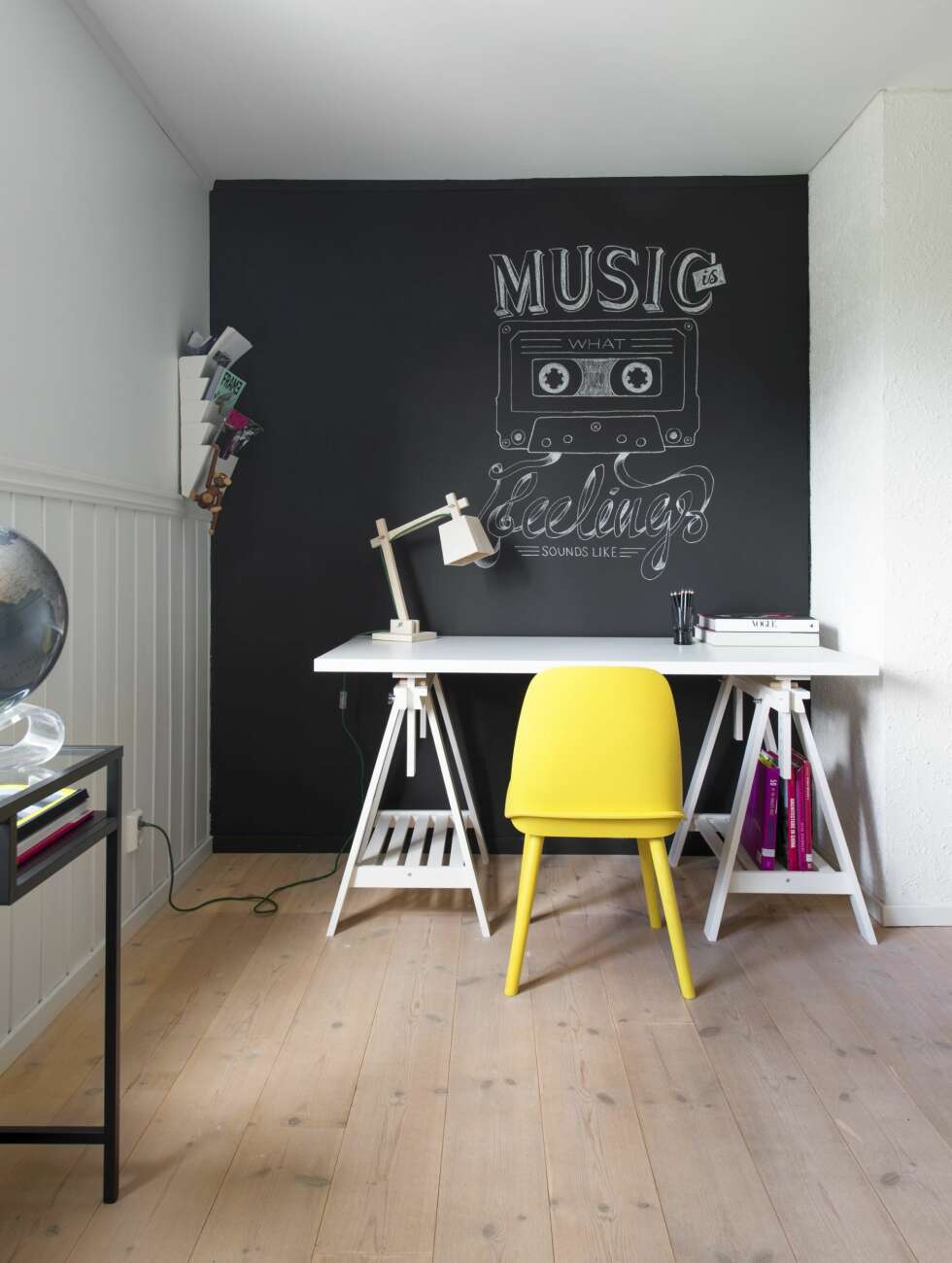 Musikalsk skrivekrok. Endeveggen ble malt med tavlemaling og fikk musikk-inspirert krittmotiv.
Skrivebordet er fra Ikea, magasin-hyllen likeså. Den gule stolen og trelampen på bordet er begge fra Muuto. Musikalsk skrivekrok. Endeveggen ble malt med tavlemaling og fikk musikk-inspirert krittmotiv.
Skrivebordet er fra Ikea, magasin-hyllen likeså. Den gule stolen og trelampen på bordet er begge fra Muuto.