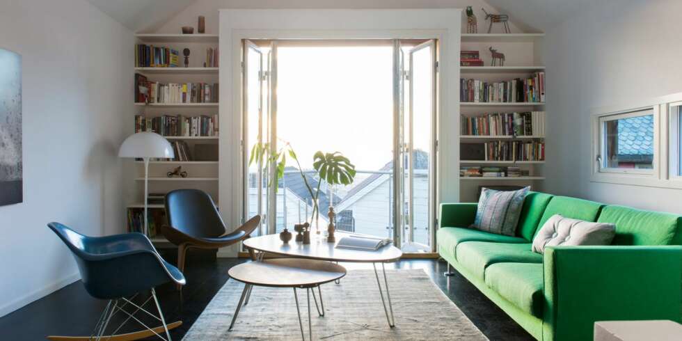 STEMNINGSFULLT: Stuen er i likhet med huset smalt og høyt. Rommet henvender seg mot balkongen i sør, mot lyset, og utsikten. Park Sofa og Eames Plastic Armchair fra Vitra. Sofabord, teppe og Shell Chair fra Verket interiør. Bokhyllene på hver side av foldedørene er tegnet av arkitekt Søren Sandved. Styling: Juni Hjartholm. STEMNINGSFULLT: Stuen er i likhet med huset smalt og høyt. Rommet henvender seg mot balkongen i sør, mot lyset, og utsikten. Park Sofa og Eames Plastic Armchair fra Vitra. Sofabord, teppe og Shell Chair fra Verket interiør. Bokhyllene på hver side av foldedørene er tegnet av arkitekt Søren Sandved. Styling: Juni Hjartholm.