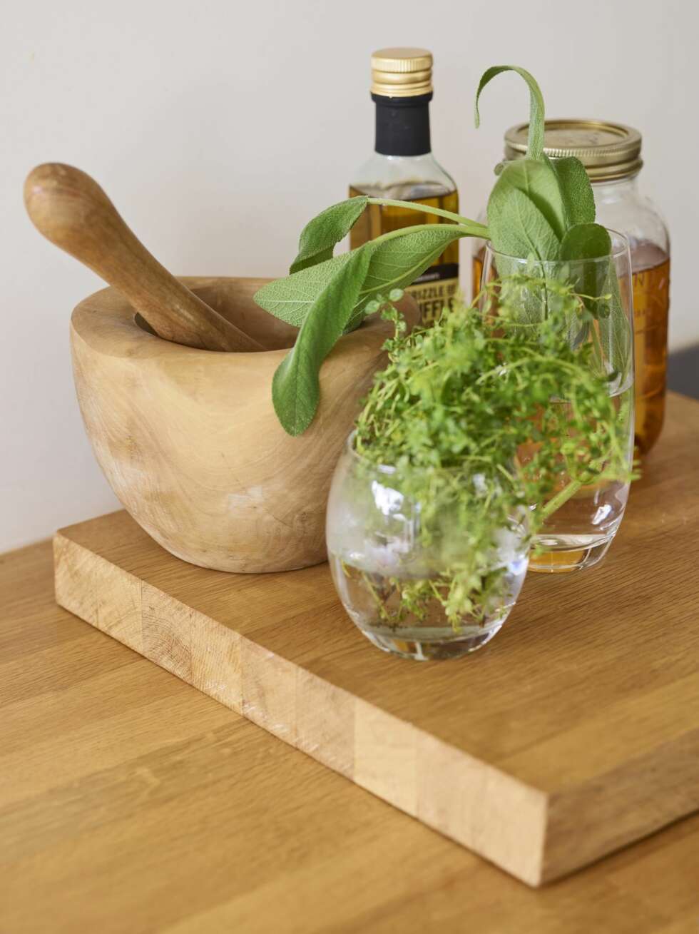 Urtene er salvie og timian fra hagen i glassene på trefjølen, og det er hjemmelaget rosmarinolje i den store glasskrukken bak. Styling: Tone Kroken. Urtene er salvie og timian fra hagen i glassene på trefjølen, og det er hjemmelaget rosmarinolje i den store glasskrukken bak. Styling: Tone Kroken.