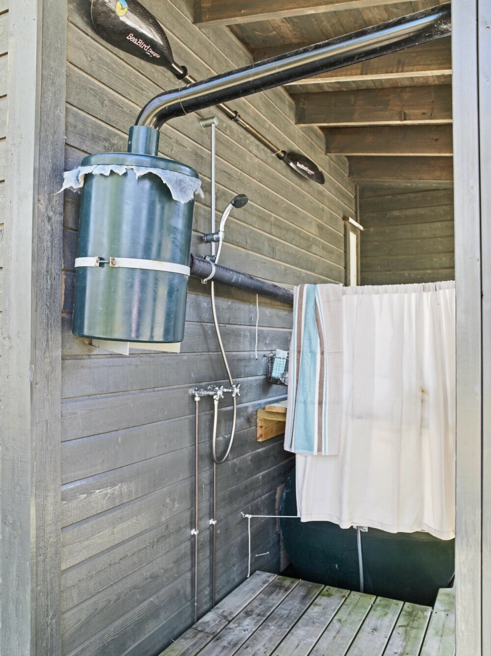 DUSJLØSNINGEN: Utedusjen er montert med trykkstyrt pumpe fra sisternen. En gardin med maljer gir nødvendig avskjerming. Foto: Inger Mette Meling Kostveit DUSJLØSNINGEN: Utedusjen er montert med trykkstyrt pumpe fra sisternen. En gardin med maljer gir nødvendig avskjerming. Foto: Inger Mette Meling Kostveit