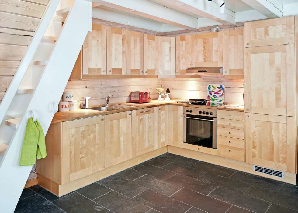 ÅPEN LØSNING: Kjøkkenet fra Ikea har åpen løsning mot stuen. Taket og trappen opp til hemsen er malt i hvitt for å gi hytta et lysere uttrykk. FOTO: Sveinung Bråthen. ÅPEN LØSNING: Kjøkkenet fra Ikea har åpen løsning mot stuen. Taket og trappen opp til hemsen er malt i hvitt for å gi hytta et lysere uttrykk. FOTO: Sveinung Bråthen.