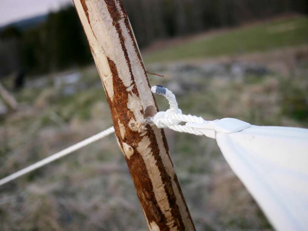 Påler: Du trenger to påler; en høy foran og
en lav bak. Høyden på den fremre bør være
slik at du har ståhøyde under duken, den
bak bør være så høy at du kan sitte uten å
stange i duken. Lag ett eller flere hull som
du trær bardunen igjennom. Påler: Du trenger to påler; en høy foran og
en lav bak. Høyden på den fremre bør være
slik at du har ståhøyde under duken, den
bak bør være så høy at du kan sitte uten å
stange i duken. Lag ett eller flere hull som
du trær bardunen igjennom.