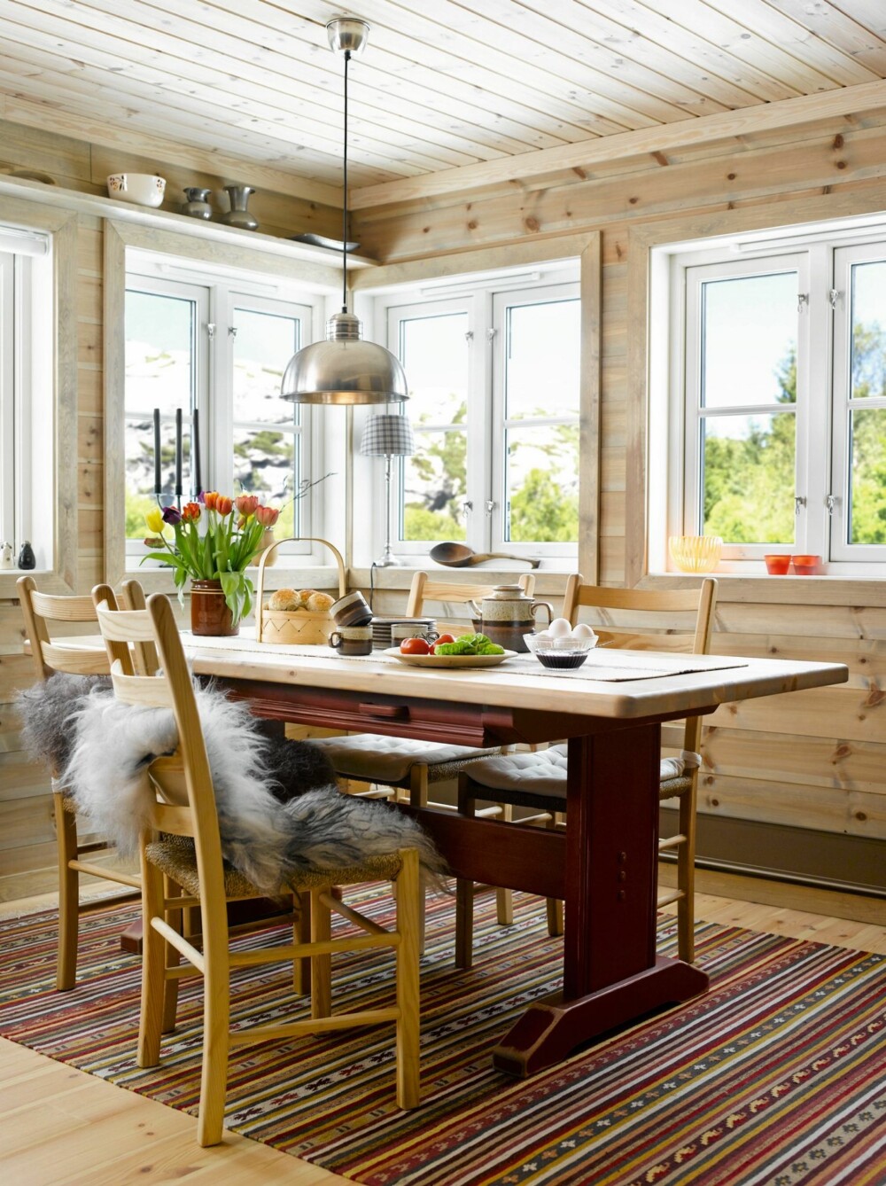 ROMSLIG SPISEKROK: Rundt det nye, spesialtilpassede spisebordet samler hytteeierne familie og venner. Teppet fant de på Ikea, og fargene stemte perfekt med den øvrige fargepaletten. ROMSLIG SPISEKROK: Rundt det nye, spesialtilpassede spisebordet samler hytteeierne familie og venner. Teppet fant de på Ikea, og fargene stemte perfekt med den øvrige fargepaletten.