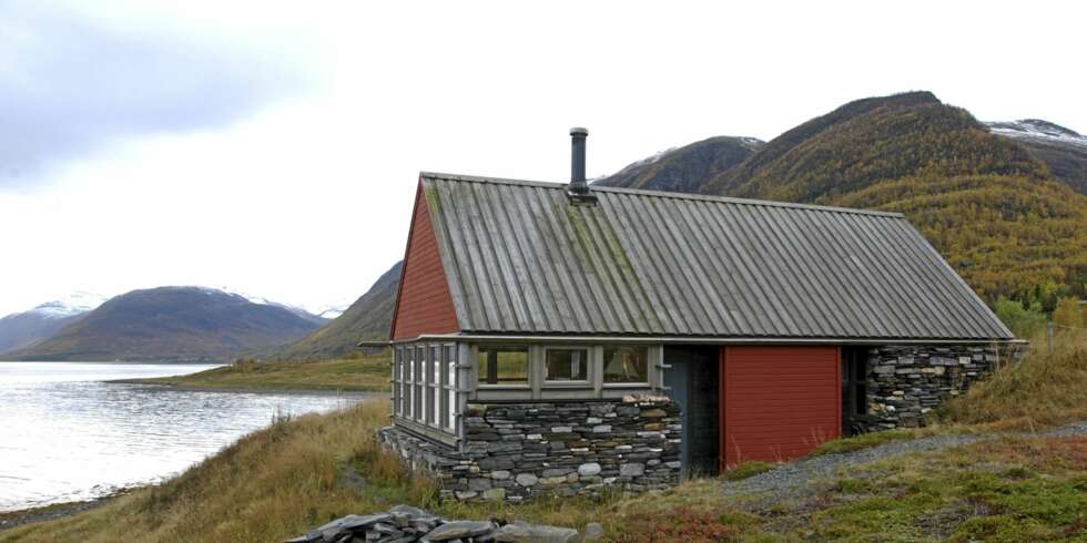 STERK KOMBINASJON: Kontrasten mellom den helt åpne fronten og den lukkete indre og den nedgravde soveromsdelen av hytta er godt synlig utenfra. Taket er festet med stålbånd, skjult i veggene for at det ikke skal blåse bort i heftige stormkast. Rødfargen er en mye brukt valør i dette området. STERK KOMBINASJON: Kontrasten mellom den helt åpne fronten og den lukkete indre og den nedgravde soveromsdelen av hytta er godt synlig utenfra. Taket er festet med stålbånd, skjult i veggene for at det ikke skal blåse bort i heftige stormkast. Rødfargen er en mye brukt valør i dette området.
