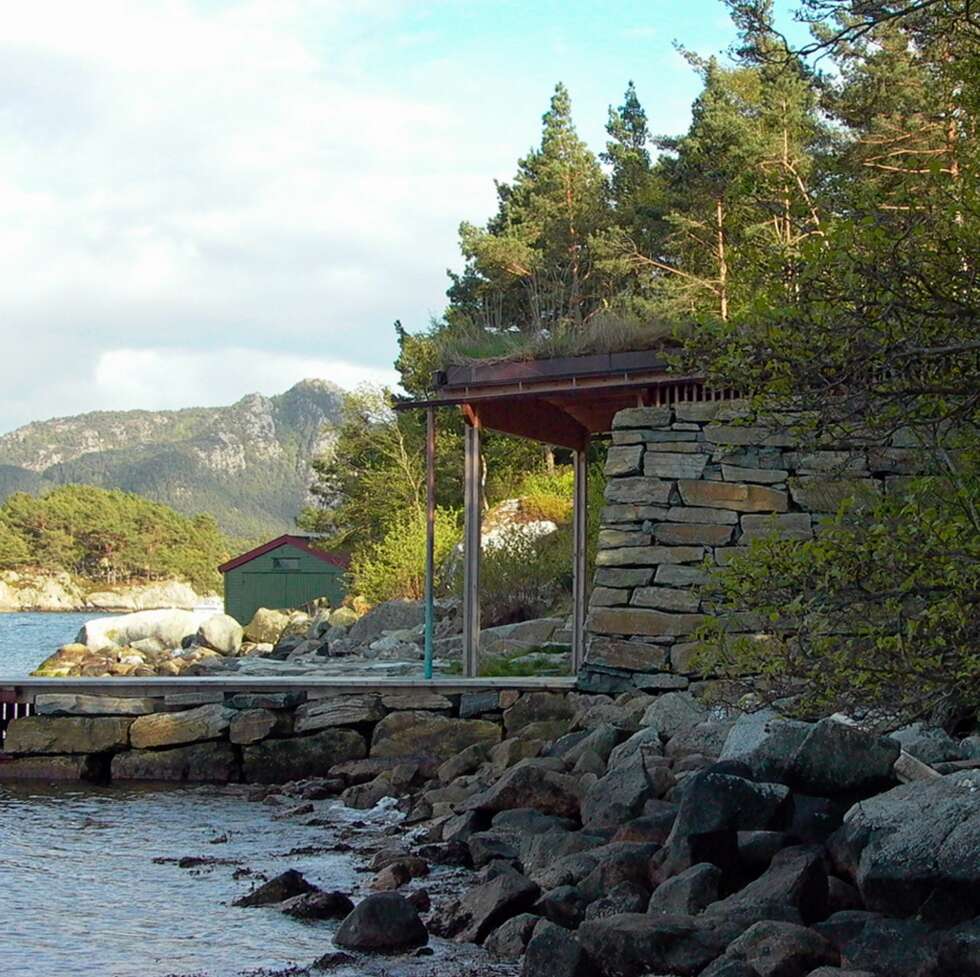 FORSVINNER I FJÆRA: Fra siden går naustet av gråstein og treverk nesten i ett med landskapet. FORSVINNER I FJÆRA: Fra siden går naustet av gråstein og treverk nesten i ett med landskapet.