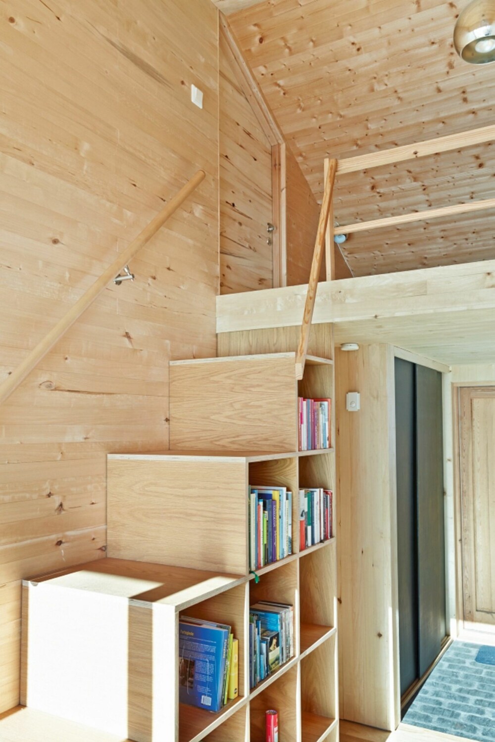 BOKHYLLETRAPP: I biblioteket ved inngangspartiet har arkitekten laget en original trappehylle opp til hemsen. Trappen er laget av eikefiner, og har 60 cm brede trinn som er 40 cm høye. BOKHYLLETRAPP: I biblioteket ved inngangspartiet har arkitekten laget en original trappehylle opp til hemsen. Trappen er laget av eikefiner, og har 60 cm brede trinn som er 40 cm høye.