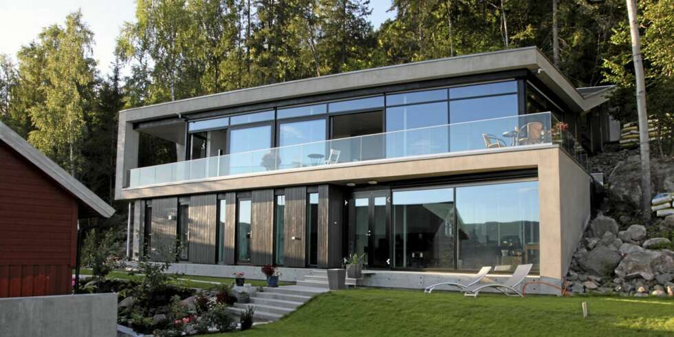 ET BLIKKFANG: Fra utsiden ser vi hvordan de to hovedetstasjene i mur- og glassvillaen åpner seg raust mot utsikten. ET BLIKKFANG: Fra utsiden ser vi hvordan de to hovedetstasjene i mur- og glassvillaen åpner seg raust mot utsikten.
