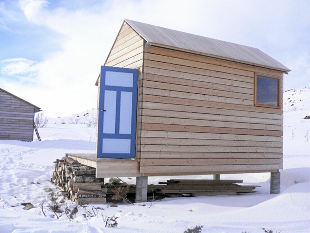 STILRENT I KRITTHVIT SNØ: Lie Øyen Arkitekter tegnet annekset i den samme rene, stramme stil som hovedhuset. Det inneholder biotoalett og vedbod. De lyseblå dørene er gjenbruk; et kjært minne fra den gamle, lille hytta som sto på denne tomten. STILRENT I KRITTHVIT SNØ: Lie Øyen Arkitekter tegnet annekset i den samme rene, stramme stil som hovedhuset. Det inneholder biotoalett og vedbod. De lyseblå dørene er gjenbruk; et kjært minne fra den gamle, lille hytta som sto på denne tomten.
