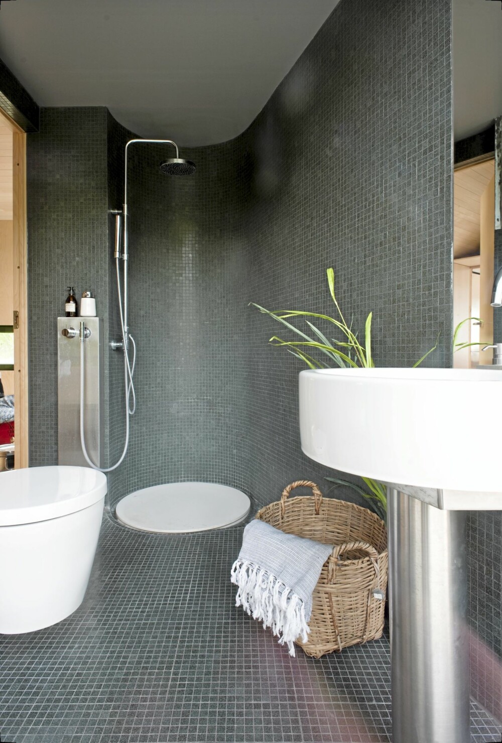 SAKRAL STEMNING Badet ligger i enden av hytta som vender mot land. Mørk, grågrønn Bisazza glassmosaikkfliser. Dusjbunn i hvit Corian, laget etter mål. SAKRAL STEMNING Badet ligger i enden av hytta som vender mot land. Mørk, grågrønn Bisazza glassmosaikkfliser. Dusjbunn i hvit Corian, laget etter mål.