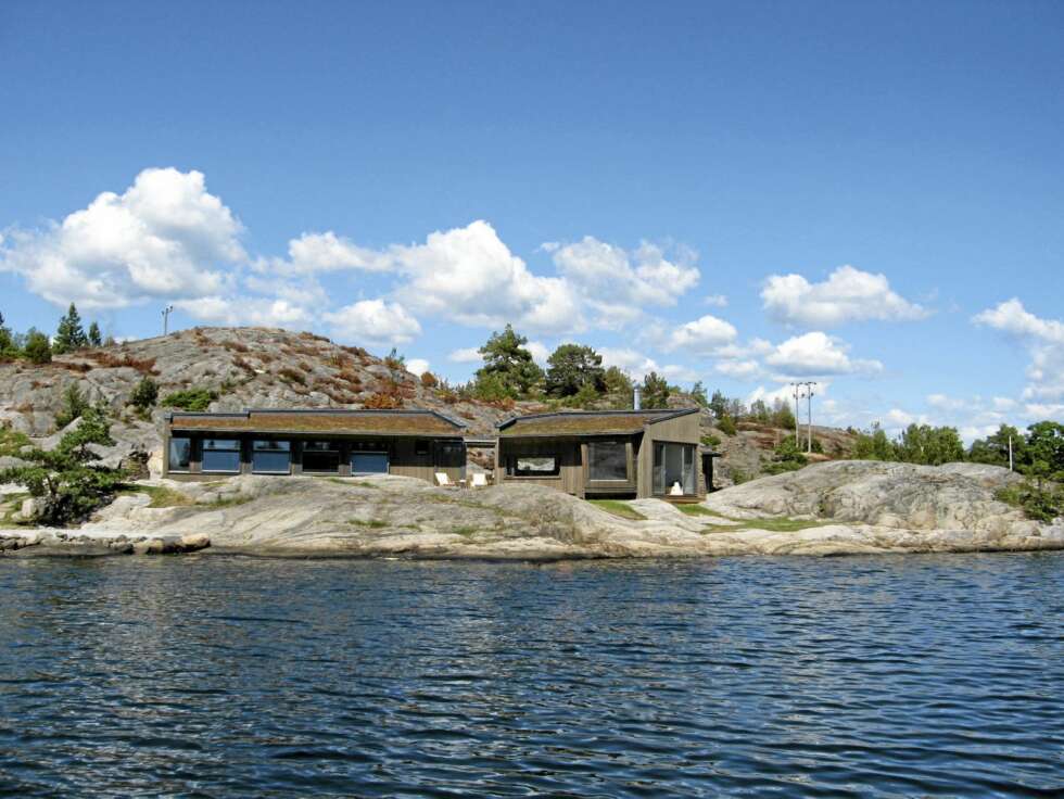HYTTE I ETT MED HOLMEN: Fra sjøen er det mulig se hvordan den nye sommerhytta som erstattet en gammel en, har fått en spenstig, men like vel diskre form. Materialer og farger er også utvalgte for å matsje miljøet. Taket er tekket med et såkalt mosetak. HYTTE I ETT MED HOLMEN: Fra sjøen er det mulig se hvordan den nye sommerhytta som erstattet en gammel en, har fått en spenstig, men like vel diskre form. Materialer og farger er også utvalgte for å matsje miljøet. Taket er tekket med et såkalt mosetak.