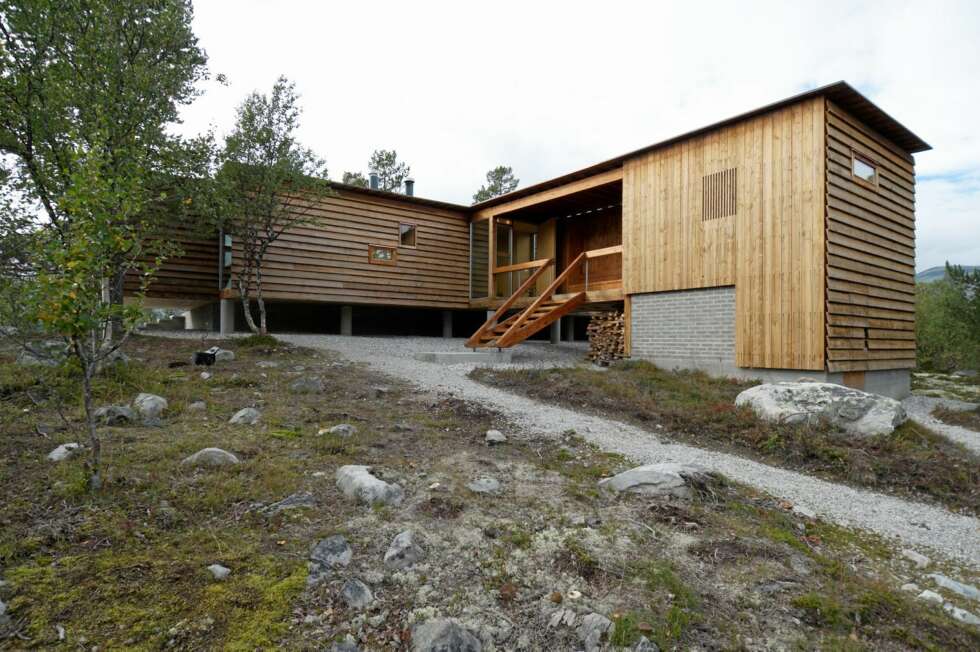 ET HYTTE I SÆRKLASSE: Det to-etasjers våtromhuset ligger mot øst og morgensolen. Vindfanget i midten binder sammen de to bygningskroppene og gir ly til de to inngangene. ET HYTTE I SÆRKLASSE: Det to-etasjers våtromhuset ligger mot øst og morgensolen. Vindfanget i midten binder sammen de to bygningskroppene og gir ly til de to inngangene.