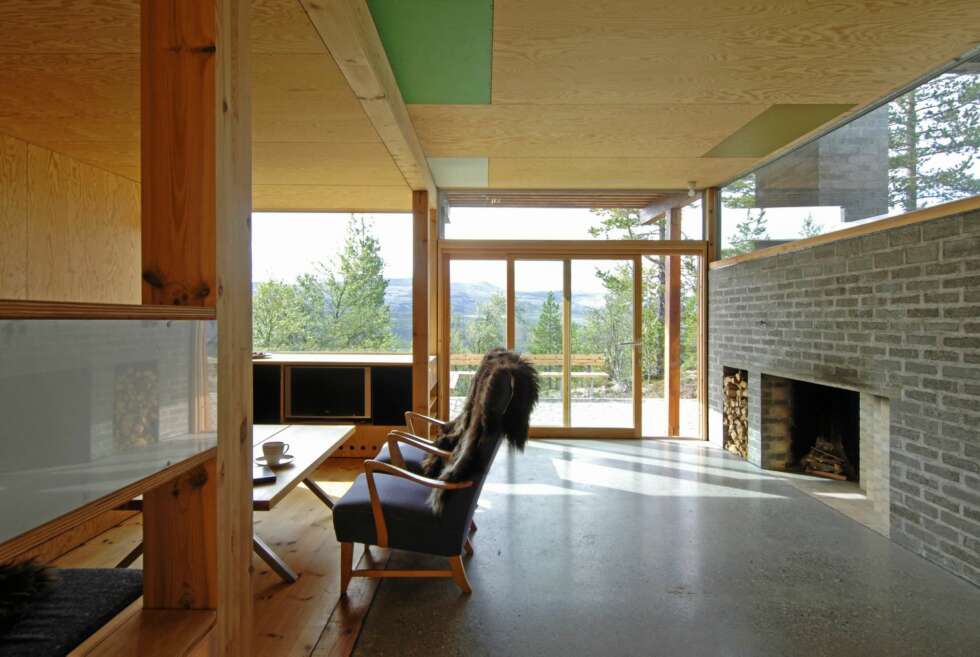 STUE MED STIL: Stuegulvet er i slipt betong, og peisen er oppført i matchende betongstein. Den lave bokreolen ved vinduet er også signert arkitekten. STUE MED STIL: Stuegulvet er i slipt betong, og peisen er oppført i matchende betongstein. Den lave bokreolen ved vinduet er også signert arkitekten.