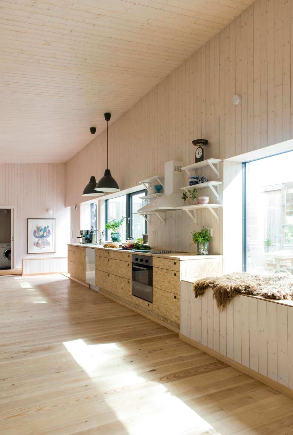 LANGSTRAKT OG HØYREIST ALLROM: Inngangen til hovedhuset er i enden av allrommet, i øst. Kjøkkenet er plassert langs langveggen som vender mot atriet. Den rause takhøyden samsvarer med rommets utstrekning, og sørger for at volumet er lyst og luftig. LANGSTRAKT OG HØYREIST ALLROM: Inngangen til hovedhuset er i enden av allrommet, i øst. Kjøkkenet er plassert langs langveggen som vender mot atriet. Den rause takhøyden samsvarer med rommets utstrekning, og sørger for at volumet er lyst og luftig.