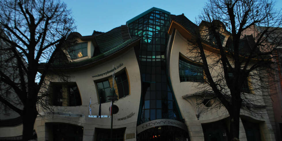 Taket på ""The Crooked House"" er dekket med metallplater og glasserte takstein i grønne og blå nyanser, noe som skal gi en illusjon av drageskjell. FOTO: <a href=""http://www.flickr.com/photos/abhijeetrane/3173810231/"">abhijeetrane</a> på Flicker.com. Noen <a href=""http://creativecommons.org/licenses/by/2.0/deed.en_GB"">rettigheter</a> reservert. Taket på ""The Crooked House"" er dekket med metallplater og glasserte takstein i grønne og blå nyanser, noe som skal gi en illusjon av drageskjell. FOTO: <a href=""http://www.flickr.com/photos/abhijeetrane/3173810231/"">abhijeetrane</a> på Flicker.com. Noen <a href=""http://creativecommons.org/licenses/by/2.0/deed.en_GB"">rettigheter</a> reservert.