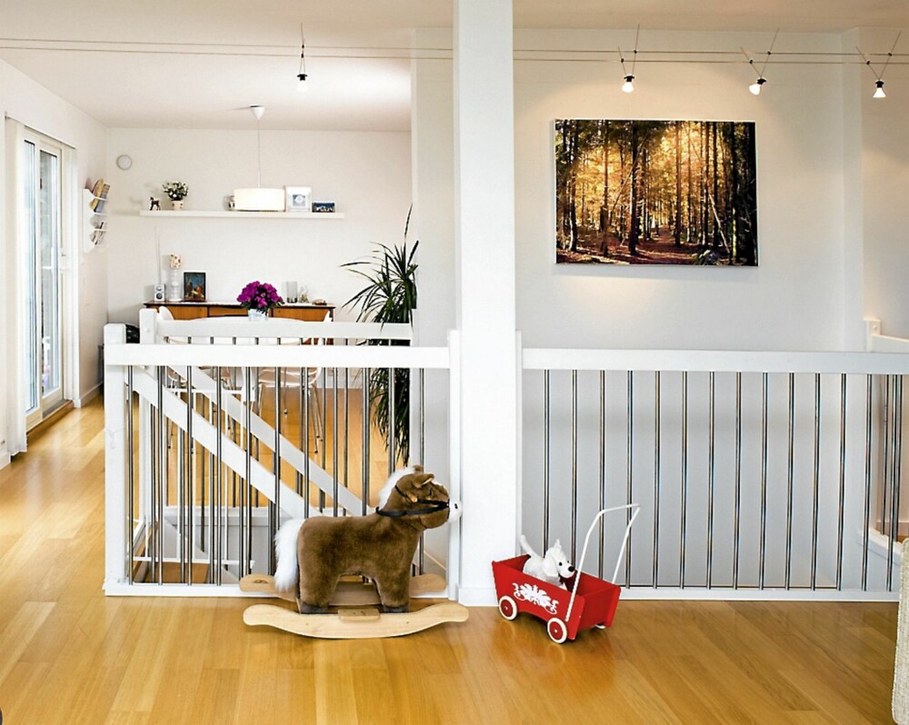 TILPASNINGER: Huset kom med eikeparkett og hvite vegger. På grunn av barna har Mette og Åsmund montert en grind fra Ikea foran den bratte trappen. Bildet på veggen er fra skogen utenfor huset, og er tatt av Mette. TILPASNINGER: Huset kom med eikeparkett og hvite vegger. På grunn av barna har Mette og Åsmund montert en grind fra Ikea foran den bratte trappen. Bildet på veggen er fra skogen utenfor huset, og er tatt av Mette.