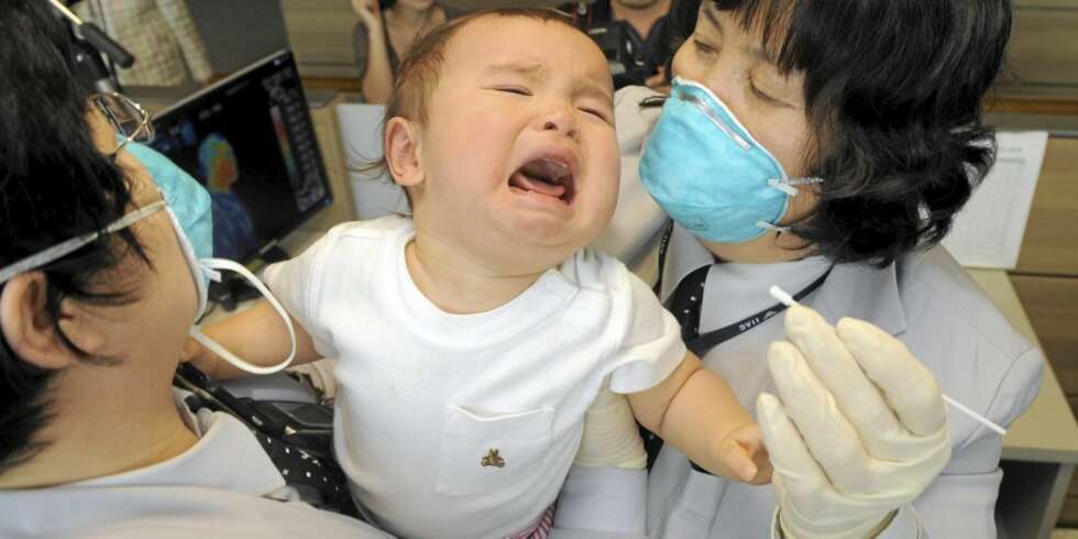 TESTES FOR INFLUENSA: Sør-Koreansk helsepersonell forsøker å ta en prøve av en baby som har ankommet med fly fra USA. TESTES FOR INFLUENSA: Sør-Koreansk helsepersonell forsøker å ta en prøve av en baby som har ankommet med fly fra USA.