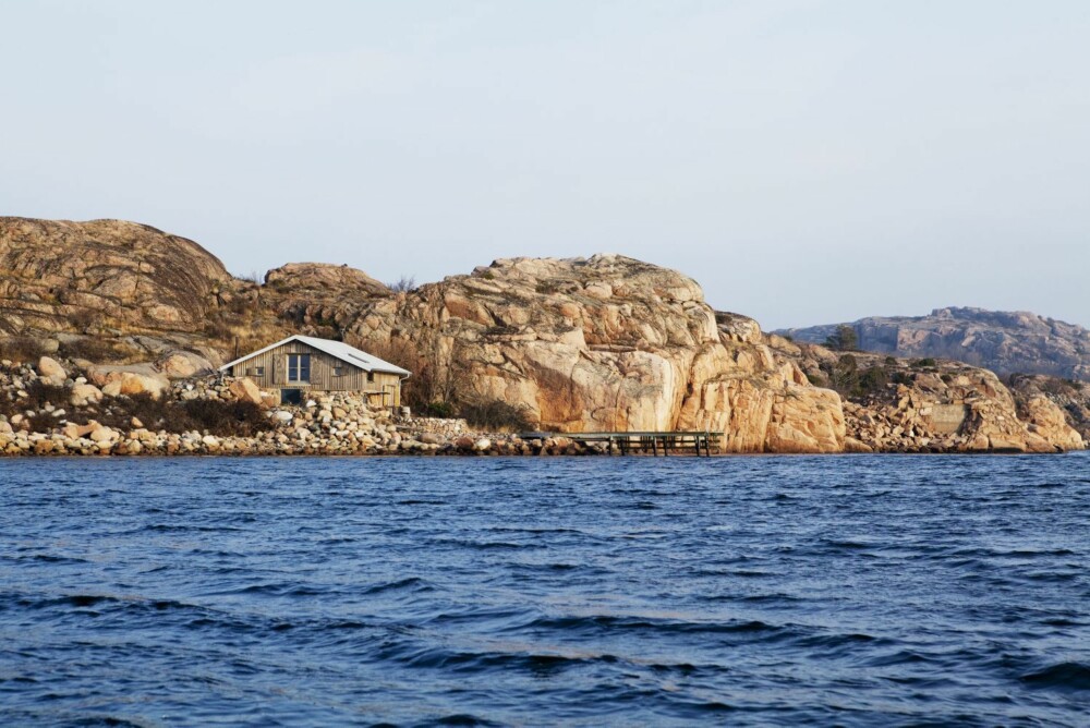 I ett med omgivelsene: Hytta har samme nyanser som fjellet, og smelter sammen med naturen rundt. Den ligger på en odde med steinstranden klatrende opp mot fasaden. Innenfor i viken er det en sandstrand. Man når hytta best med båt, det er derfor nødvendig med en solid brygge. I ett med omgivelsene: Hytta har samme nyanser som fjellet, og smelter sammen med naturen rundt. Den ligger på en odde med steinstranden klatrende opp mot fasaden. Innenfor i viken er det en sandstrand. Man når hytta best med båt, det er derfor nødvendig med en solid brygge.