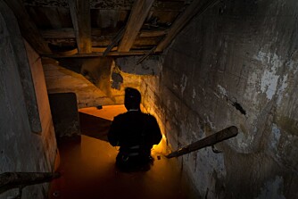 Nedgangene til bunkeren går fra gateplan og ned under bakken via en liten trapp. I dag er døra stengt, men da vi var her, sto den vid åpen uten tilsyn. Nedgangene til bunkeren går fra gateplan og ned under bakken via en liten trapp. I dag er døra stengt, men da vi var her, sto den vid åpen uten tilsyn.