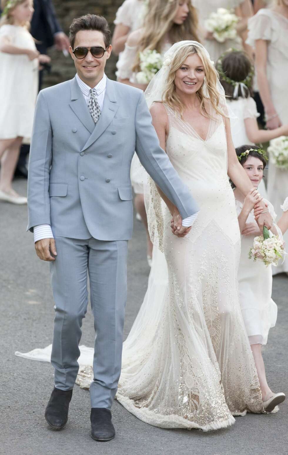 Kate Moss bar en kremhvit, vintage-inspirert brudekjole dekket med gullbroderier og strass. Kate Moss bar en kremhvit, vintage-inspirert brudekjole dekket med gullbroderier og strass.
