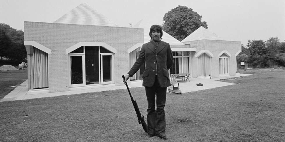 TRIGGERHAPPY: Keith Moon poserer med rifle foran «Tara». Hans festing og ville livsstil på denne eiendommen gjør at de aller fleste tror det var han som fikk bygget pyramidehuset. Soverommet kan skimtes i pyramiden til venstre for Keith. TRIGGERHAPPY: Keith Moon poserer med rifle foran «Tara». Hans festing og ville livsstil på denne eiendommen gjør at de aller fleste tror det var han som fikk bygget pyramidehuset. Soverommet kan skimtes i pyramiden til venstre for Keith.