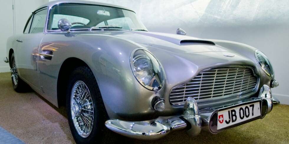 GOLDFINGER: Aston Martin DB5 - blant verdens mest berømte biler. Spilte en av hovedrollene i Goldfinger fra 1964, og dukket også opp i Thunderball året etter. Den har også dukket opp i varierende grad i GoldenEye, Tomorrow Never Dies, Casino Royale og på et bilde i The World Is Not Enough. Bilen har katapultsete, 7,6 mm maskingevær, skuddsikker vindusskjerm bak og mye annet snadder. GOLDFINGER: Aston Martin DB5 - blant verdens mest berømte biler. Spilte en av hovedrollene i Goldfinger fra 1964, og dukket også opp i Thunderball året etter. Den har også dukket opp i varierende grad i GoldenEye, Tomorrow Never Dies, Casino Royale og på et bilde i The World Is Not Enough. Bilen har katapultsete, 7,6 mm maskingevær, skuddsikker vindusskjerm bak og mye annet snadder.