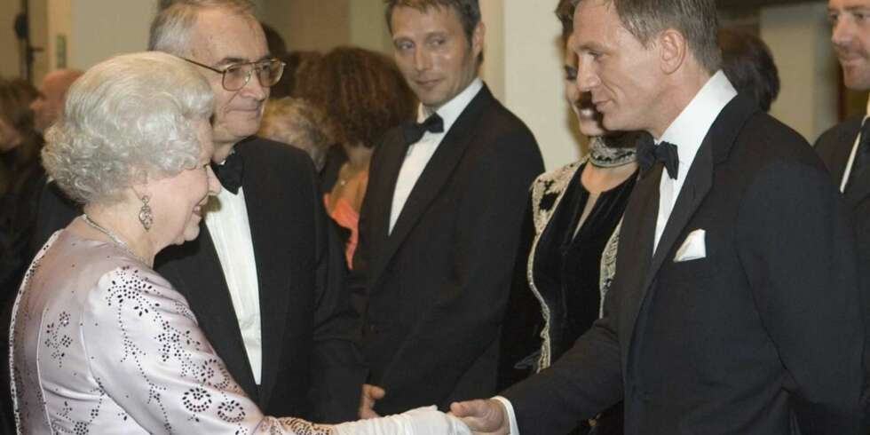 Dronning Elizabeth hilser på Daniel Craig. Mads Mikkelsen i bakgrunnen. Dronning Elizabeth hilser på Daniel Craig. Mads Mikkelsen i bakgrunnen.