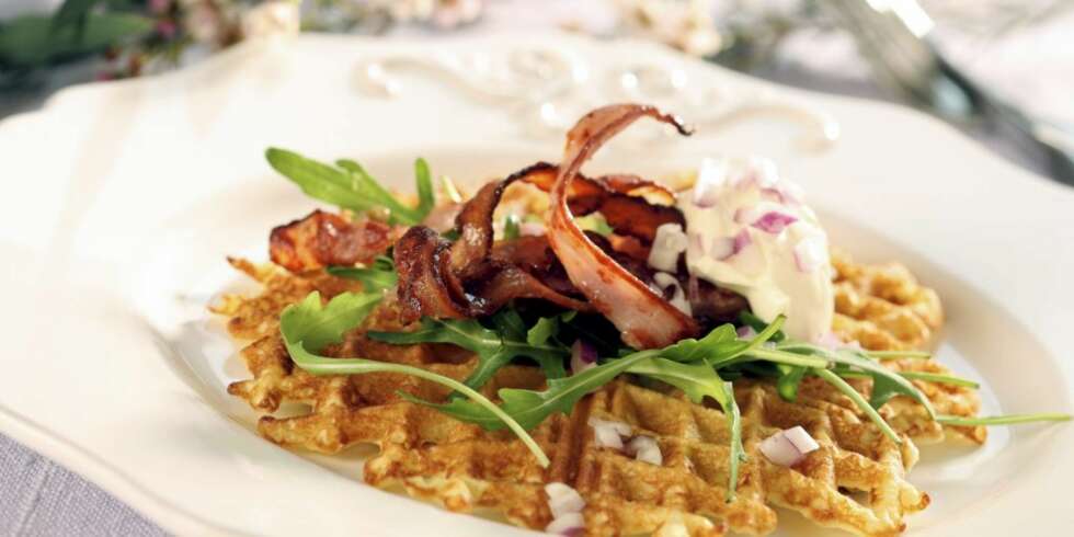 Riv litt rå potet i vaffelrøren og stek sprø vafler som toppes med bacon og rømme. En lekker, liten forrett eller kveldsrett. Riv litt rå potet i vaffelrøren og stek sprø vafler som toppes med bacon og rømme. En lekker, liten forrett eller kveldsrett.