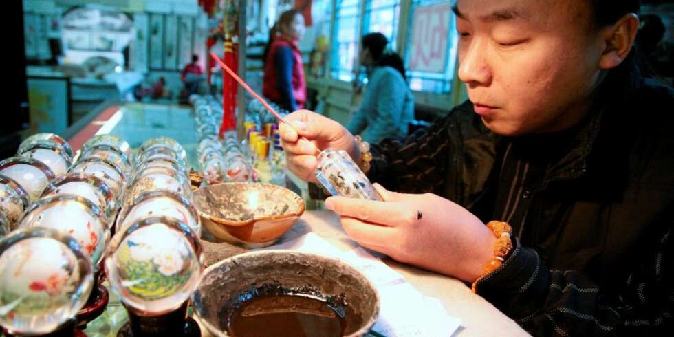 MINIATYRMALER: Xu Bu har tatt opp kunsten å male på innsiden av små glassflasker fra faren og farfaren sin. Nå driver han en butikk i den sjarmerende Beijing-handlegaten Liulichang. MINIATYRMALER: Xu Bu har tatt opp kunsten å male på innsiden av små glassflasker fra faren og farfaren sin. Nå driver han en butikk i den sjarmerende Beijing-handlegaten Liulichang.