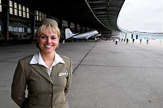 Connie Schnase serverer champagne iført 1940-talls flyvertinneuniform. Connie Schnase serverer champagne iført 1940-talls flyvertinneuniform.