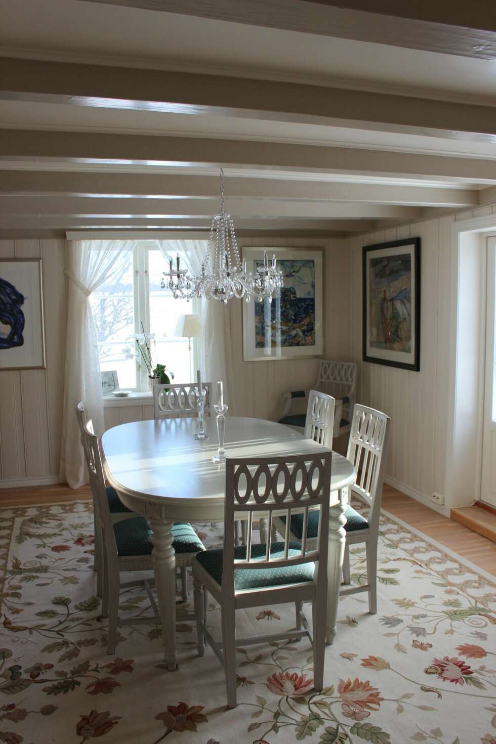 Hvitmalt spisestue med teppe med blomstermotiv og klassisk krystallkrone. Hvitmalt spisestue med teppe med blomstermotiv og klassisk krystallkrone.