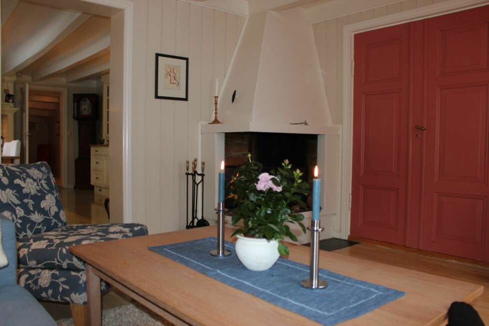 I det ene hjørnet av stuen står en koselig peis. I det ene hjørnet av stuen står en koselig peis.