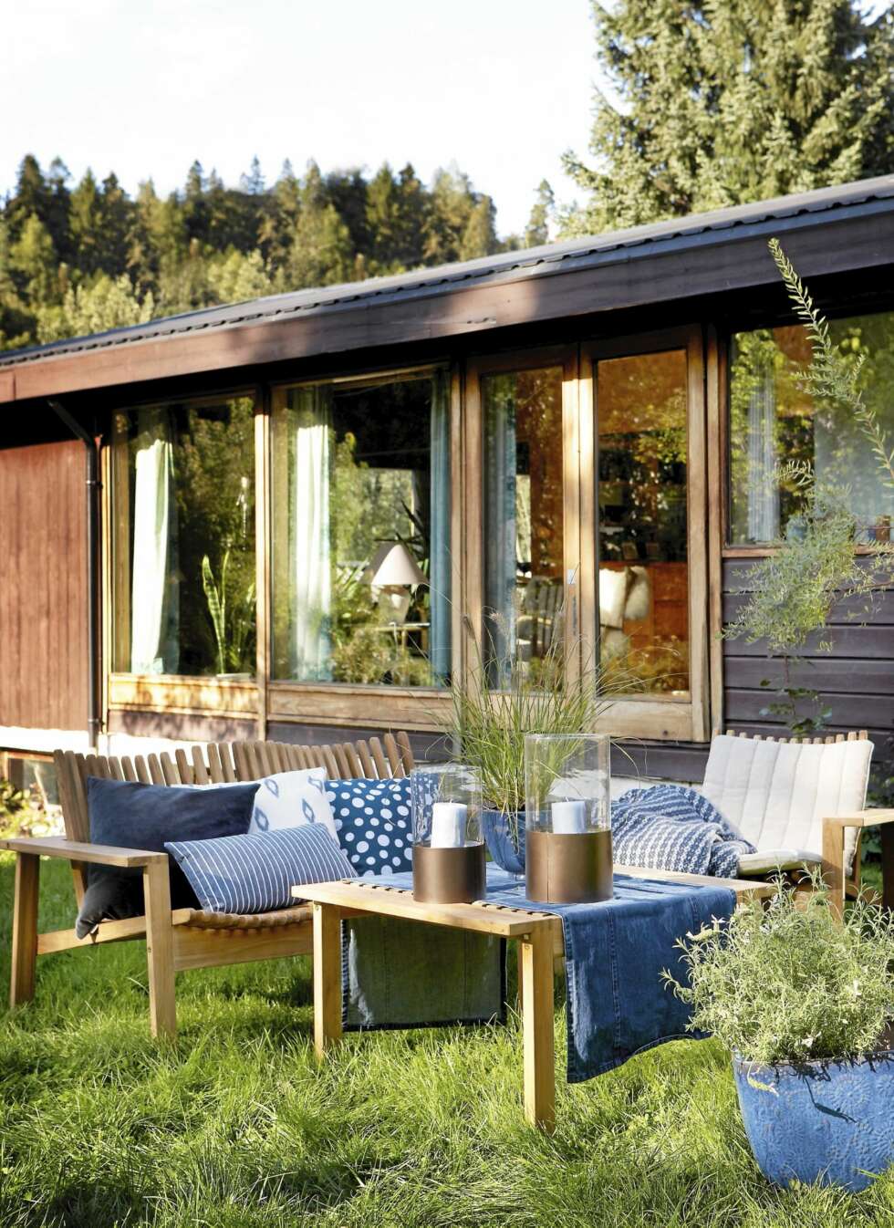 PÅ BILDET: Møbelserien Access i teak: benk, kr 7450, stoler, kr 4390 per stk., og bord, kr 3350, alt fra Berga Form/Blåmann. Løper i jeansstoff fra Lexington, kr 275, rutet ullpledd fra Lexington, kr 1525, begge fra R.O.O.M. Blå velurpute fra Linum, kr 435, Skeidar. Prikket pute fra Au Maison, kr 250, stripet pute, kr 269, hvit pute med blått mønster, kr 359, liten lykt, kr 279, stor lykt, kr 329, alt fra Verket Interiør. Blå blomserkrukke på bordet, kr 79, blå blomsterkrukke på plenen, kr 349, begge fra Plantasjen. PÅ BILDET: Møbelserien Access i teak: benk, kr 7450, stoler, kr 4390 per stk., og bord, kr 3350, alt fra Berga Form/Blåmann. Løper i jeansstoff fra Lexington, kr 275, rutet ullpledd fra Lexington, kr 1525, begge fra R.O.O.M. Blå velurpute fra Linum, kr 435, Skeidar. Prikket pute fra Au Maison, kr 250, stripet pute, kr 269, hvit pute med blått mønster, kr 359, liten lykt, kr 279, stor lykt, kr 329, alt fra Verket Interiør. Blå blomserkrukke på bordet, kr 79, blå blomsterkrukke på plenen, kr 349, begge fra Plantasjen.