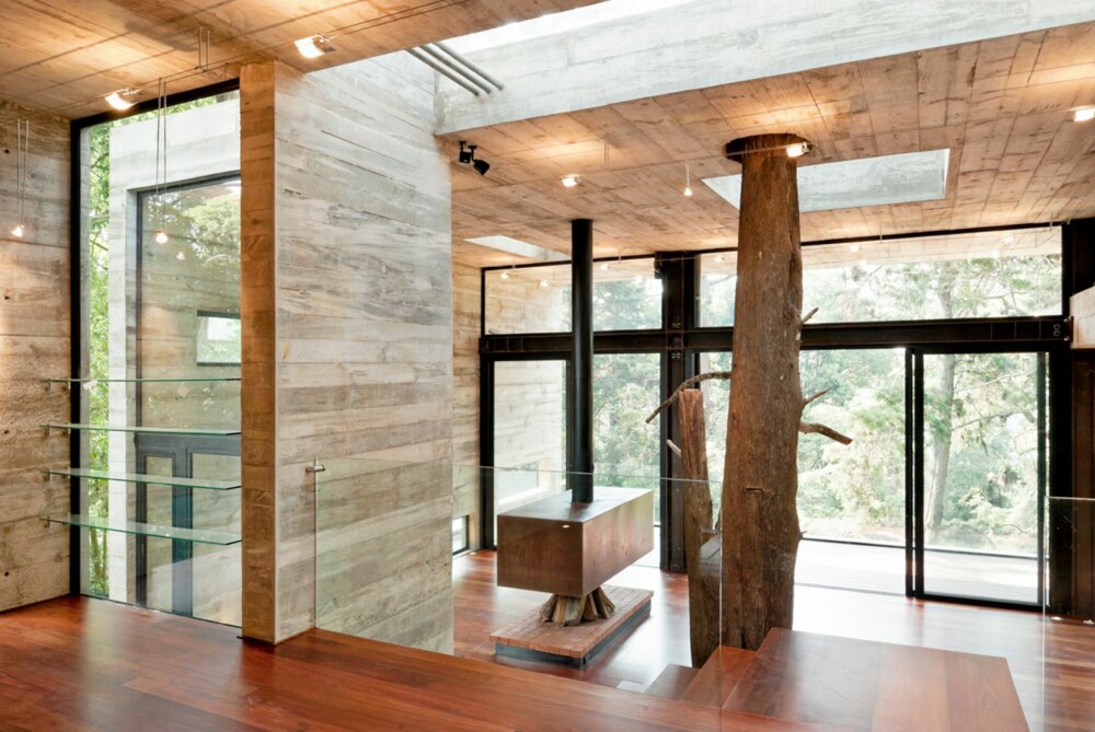 TRE OG BETONG: Glass tre og betong er gjennomgående materialer i huset. Betongveggene skaper en tøff kontrast mot de grove trestammene.