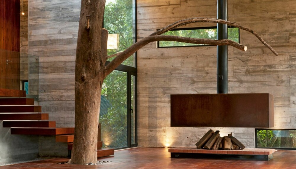 TRÆR I STUA: For å bevare skogen rundt huset har arkitektene latt trærne bli en del av arkitekturen og interiøret.