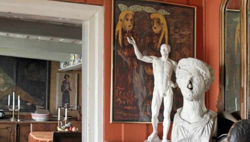 BOHEMLIV. Huset er fylt med malerier og skulpturer. Her har to skulpturer fått plass i hallen foran maleriet av Therese Nordtvedt. Den ene av stuene skimtes i bakgrunnen.