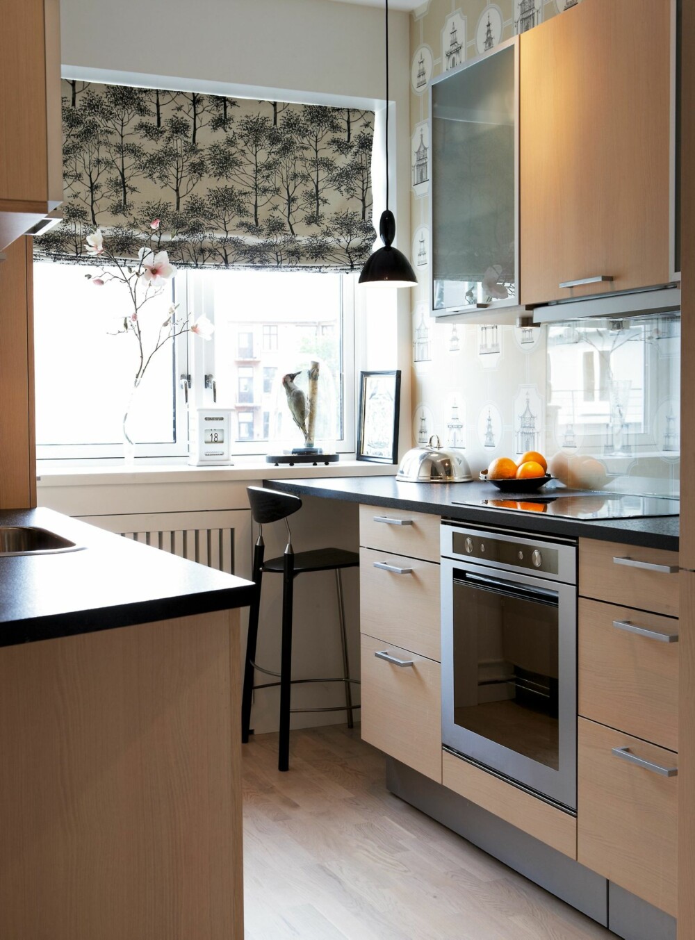 FIFFIG. Liftgardinene og tapetet har mønster i diskret fargenyanser som fungerer sammen. Sprutpanel i glass over kjøkkenbenken. I hjørnet ble det plass til et arbeidsbord. Kjøkkeninnredning og barkrakk fra HTH. FIFFIG. Liftgardinene og tapetet har mønster i diskret fargenyanser som fungerer sammen. Sprutpanel i glass over kjøkkenbenken. I hjørnet ble det plass til et arbeidsbord. Kjøkkeninnredning og barkrakk fra HTH.