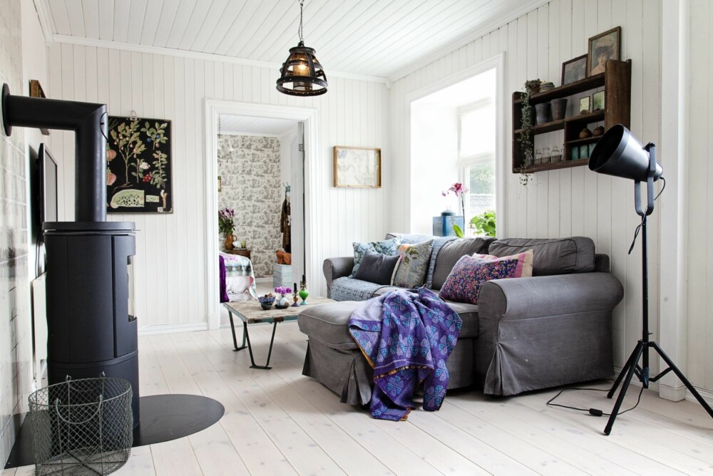 LUN STUE: Sofakroken er det innredet med myke tekstiler og puter. Den gamle trehyllen på veggen har Helene hatt med seg i mange år. Stålampen er fra Country Chic, taklampen fra Home & Cottage, stuebordet fra Nordahl, det lilla indiske tekstilet er fra Bloomingville. Vedovnen kommer fra ovnleverandøren Morsø. LUN STUE: Sofakroken er det innredet med myke tekstiler og puter. Den gamle trehyllen på veggen har Helene hatt med seg i mange år. Stålampen er fra Country Chic, taklampen fra Home & Cottage, stuebordet fra Nordahl, det lilla indiske tekstilet er fra Bloomingville. Vedovnen kommer fra ovnleverandøren Morsø.
