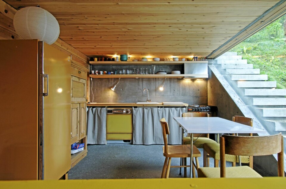 TETT SAMSPILL MED TERRENGET: Kjøkkenet i allrommet i annen etasje har gulbrune syttitalls hvitevarer som matcher tilbygget. Det slipte betonggulvet har vannbåren varme. Utetrappen til høyre går langs hele huset og ender ved den store terrassen i tredje etasje.