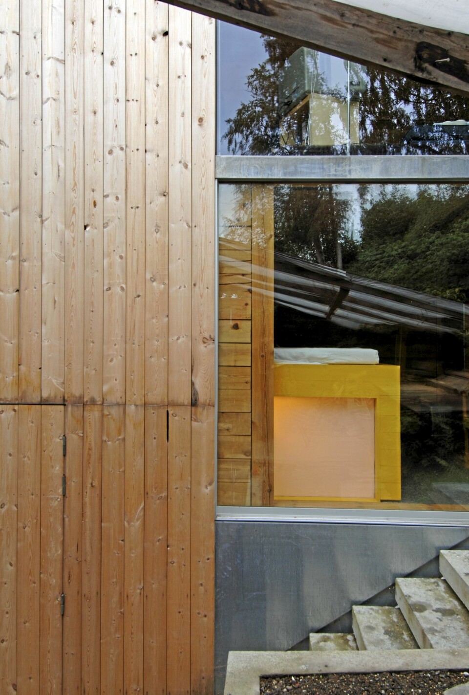 SPENSTIG ARKITEKTUR: Terrengtrappen leder til terrassen som ligger mot skrenten bak huset. Her ser vi også allrommet og en flik av det knallgule soverommet. Under det skjermer matte glass badet for innsyn. Ubehandlet furupanel.