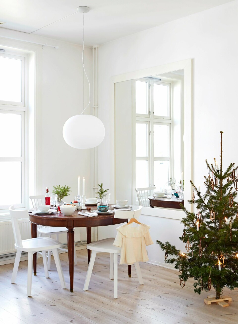 ELSKER Å DEKKE BORD: Til jul bruker hun det samme serviset som hun bruker resten av året, men små grankvister og rødt i glassene gir julestemning. Bordet er et bruktfunn. Stolene er fra Gervasoni og Norrgavel. Speilet er spesialbestilt og gir ekstra romfølelse. Julepynten på treet er fra Ann Kristin Einarsen. FOTO: Margaret M de Lange