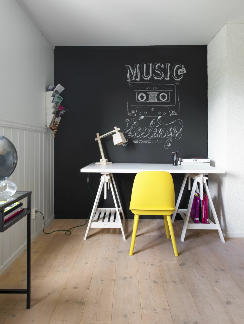 Musikalsk skrivekrok. Endeveggen ble malt med tavlemaling og fikk musikk-inspirert krittmotiv.
Skrivebordet er fra Ikea, magasin-hyllen likeså. Den gule stolen og trelampen på bordet er begge fra Muuto.