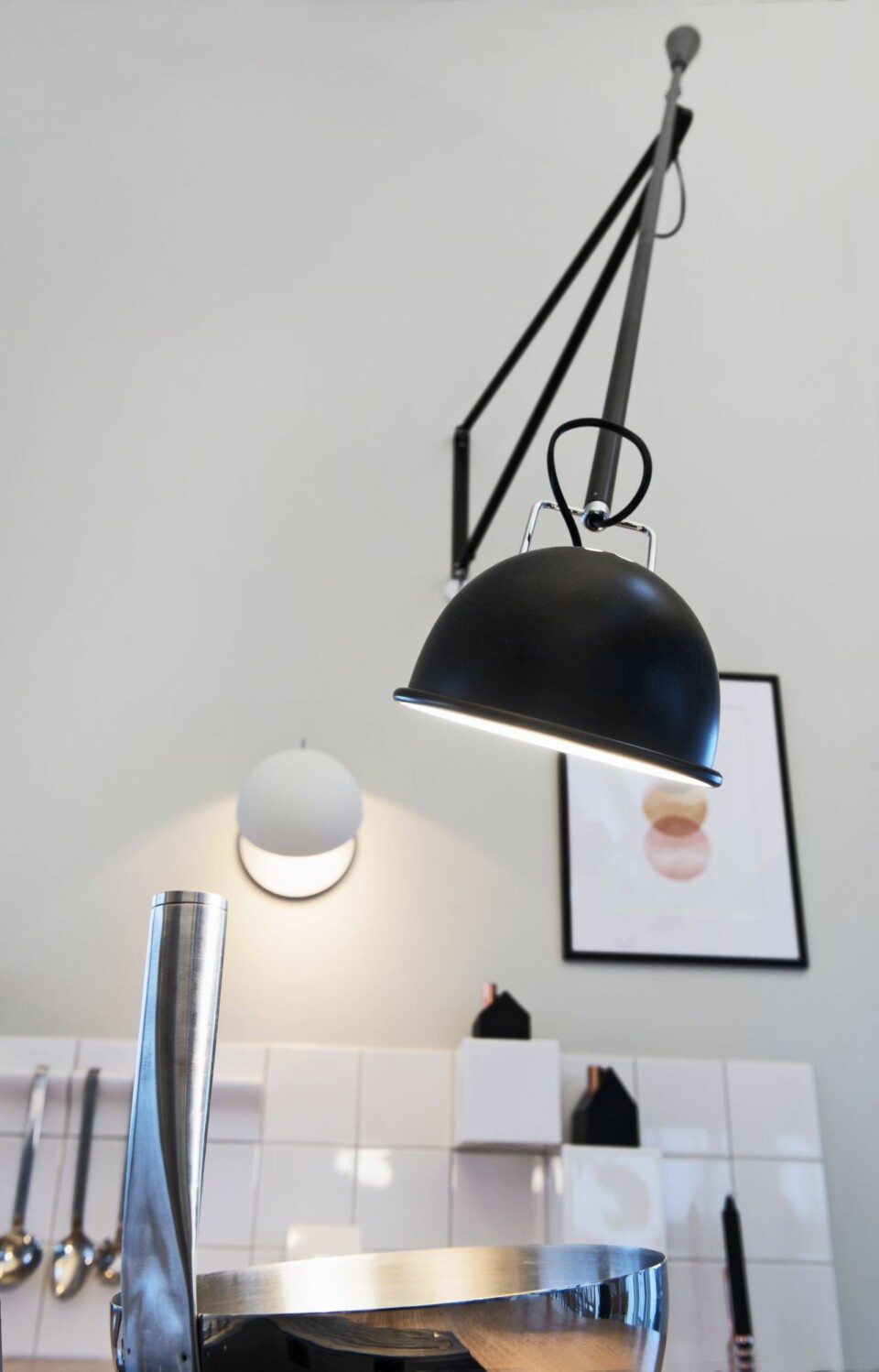 GIR ARBEIDSLYST: For å få god arbeidsbelysning over kokesonen, er det benyttet en kombinasjon av nedhengte pendler og veggmontert belysning. Lampen 265 fra Flos kan lett skyves bort når den ikke er i bruk.