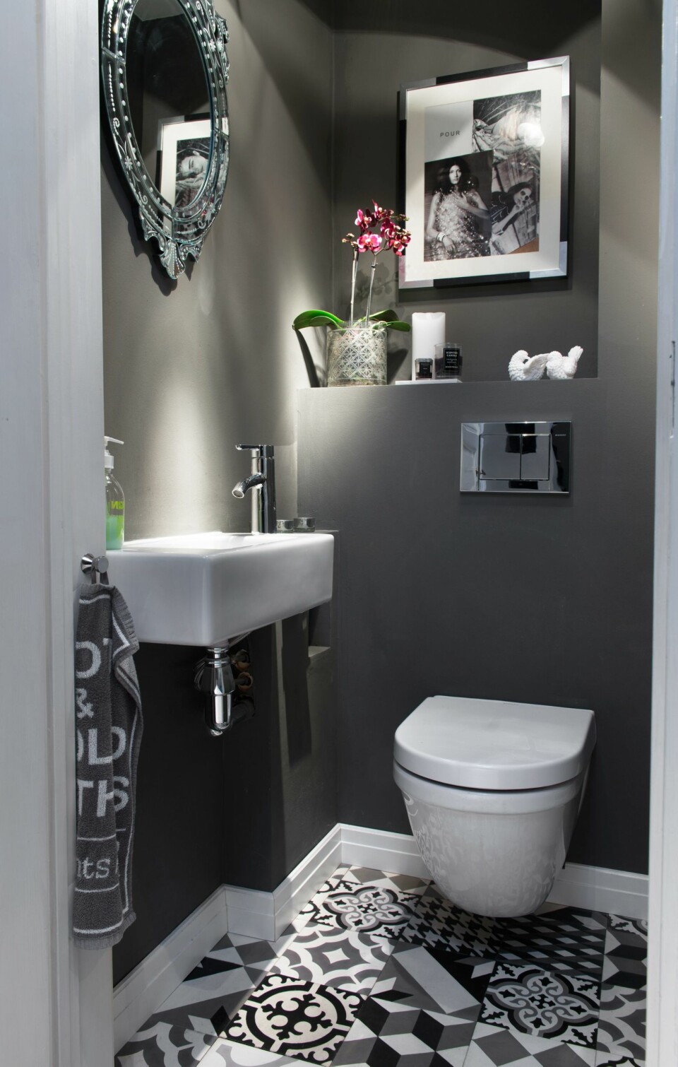 Det lille gjestetoalettet like ved inngangsdøren har fått vegger i fargen NCS S 6502-Y, matt. Flisene er en miks av forskjellige betongfliser fra Farfar.no. På hyllen står diverse loppefunn, og på veggen har Ida rammet inn utklipp fra et magasin.