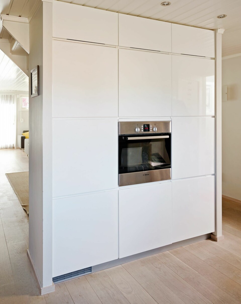 SAMLET SKAPVEGG: Veggen mellom kjøkkenet og spisestuen ble benyttet til kjøkkenskap og innebygde hvitevarer, alt fra Kvik. Passasjen til venstre gir delvis åpen løsning mot stuen.