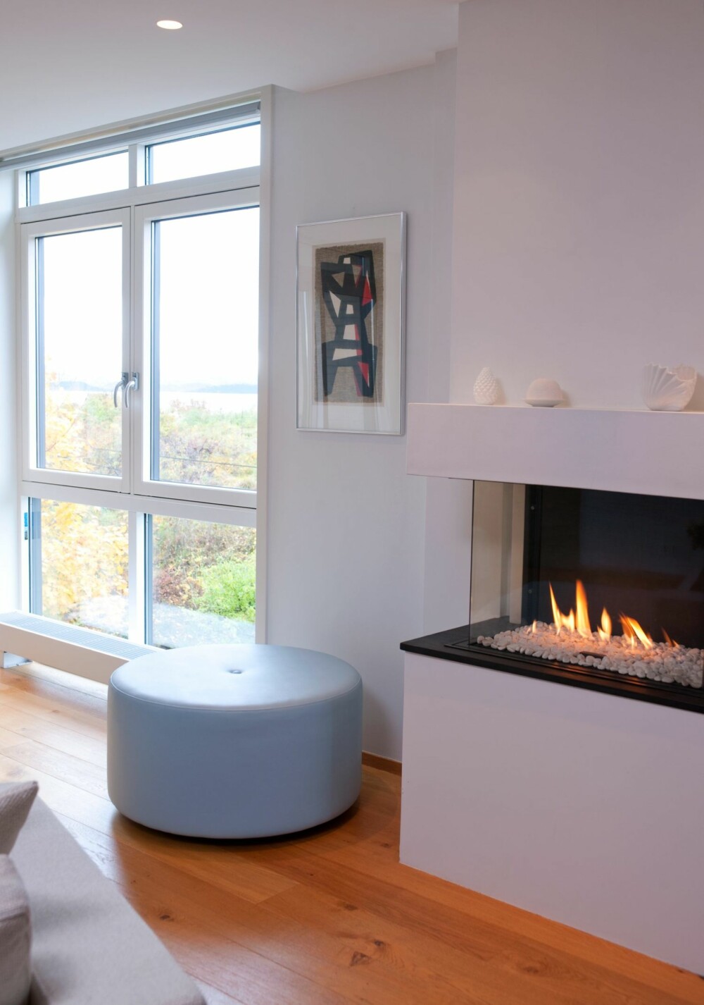 LYSEBLÅ TRÅD: Den lyseblå fargen representerer himmel og hav, og går igjen flere steder i boligen, blant annet på puffen som interiørarkitekten har designet. LYSEBLÅ TRÅD: Den lyseblå fargen representerer himmel og hav, og går igjen flere steder i boligen, blant annet på puffen som interiørarkitekten har designet.